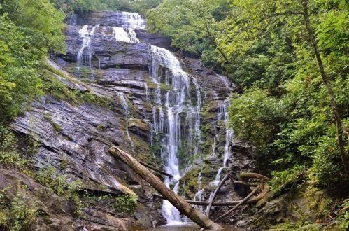 A serene waterfall cascading down rocky cliffs, surrounded by lush green trees and foliage.