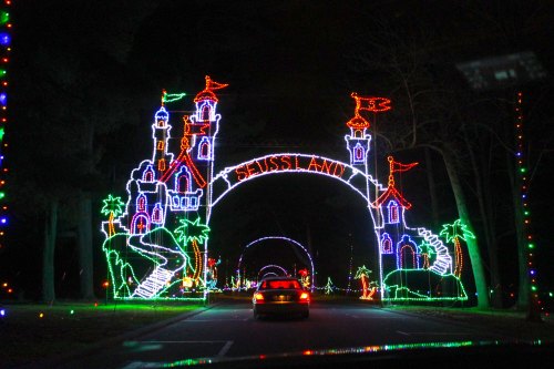 Colorful holiday lights form a whimsical castle archway, illuminating a nighttime drive through a festive display.