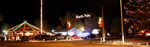 A festive night scene featuring colorful lights, a decorated tree, and a sign reading "North Pole."