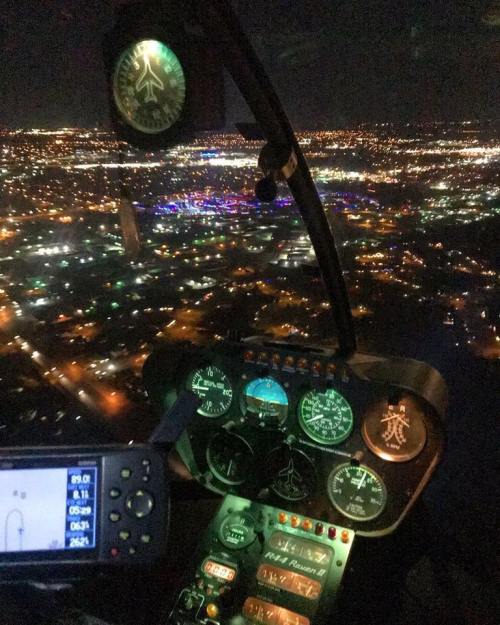 Cockpit view of a helicopter at night, showcasing illuminated city lights and various instrument gauges.