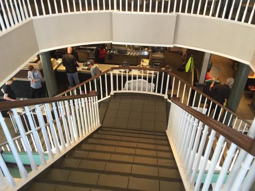 A view from above a staircase leading to a busy café with people in line and staff at the counter.