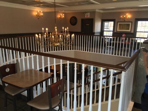 A view of a restaurant interior featuring a chandelier, wooden railings, and tables on a multi-level space.