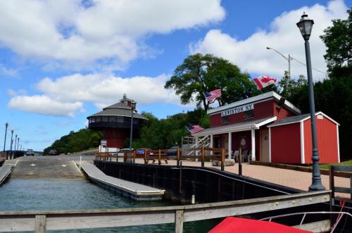 A scenic view of a harbor with a red building, flags, and a lighthouse under a partly cloudy sky.