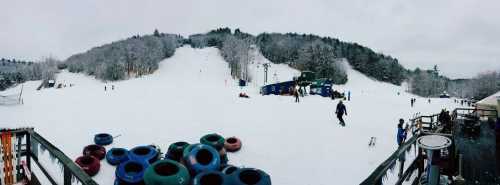 A snowy ski resort scene with people tubing and skiing, surrounded by snow-covered trees and equipment.