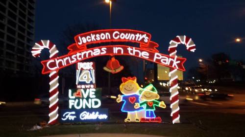 Colorful holiday sign for "Jackson County's Christmas in the Park" featuring cheerful characters and candy canes.