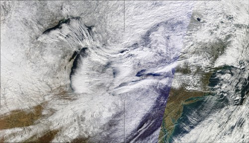 Satellite image showing a mix of clouds and land, highlighting weather patterns and terrain variations.