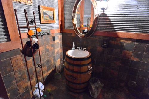 A rustic bathroom featuring a barrel sink, corrugated metal walls, and decorative items on the wall.