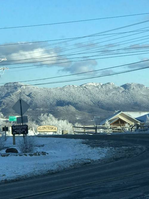 Snow-covered mountains in the background with a sign for Klonteska and a winter landscape.