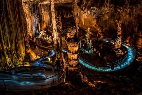 A stunning cave interior with illuminated stalagmites and stalactites, featuring winding pathways and dramatic lighting.