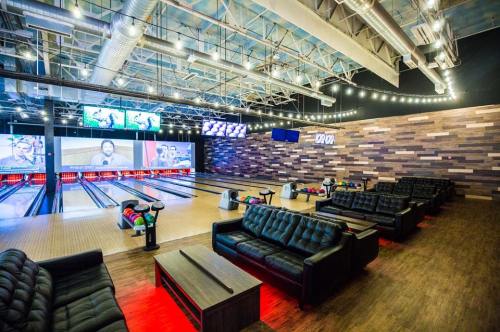 A modern bowling alley featuring lanes, seating areas, and large screens, with a stylish industrial design.