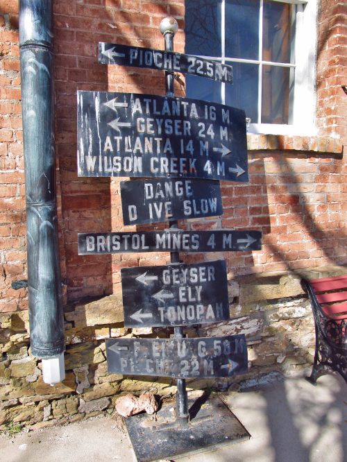 Signpost with directional arrows and distances to various locations: Pioche, Atlanta, Geyser, Wilson Creek, and more.
