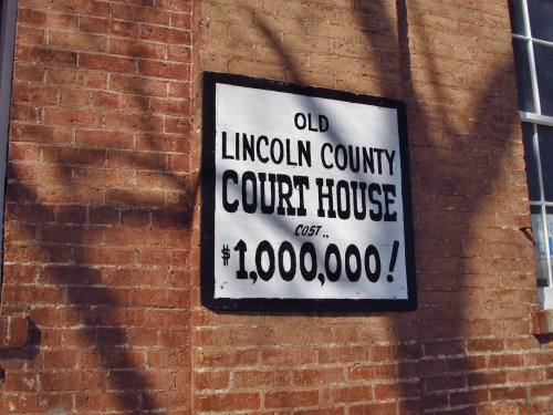Sign on a brick wall reading "Old Lincoln County Court House Cost $1,000,000!" in bold black letters.