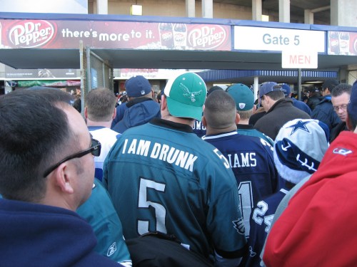 A crowd of fans wearing jerseys and hats, waiting to enter a stadium through Gate 5.