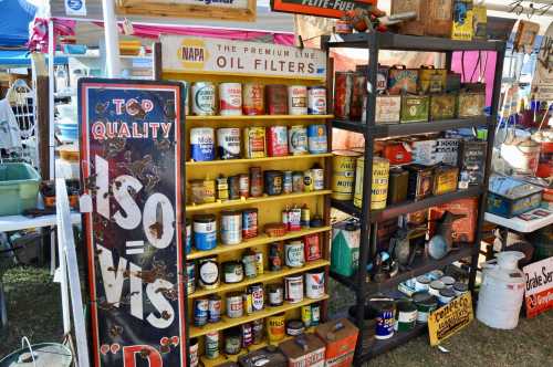 A colorful display of vintage oil cans and filters on shelves at a market, with a sign reading "Top Quality ISO VIS."