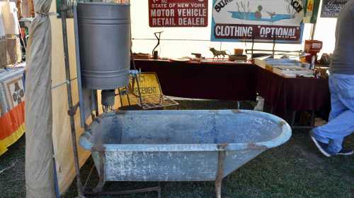 An old metal bathtub displayed at a market, with various vendor signs in the background.