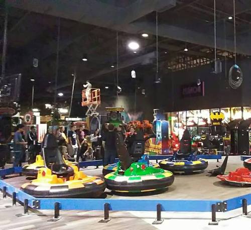 A vibrant indoor amusement area featuring colorful bumper cars and various arcade games in the background.