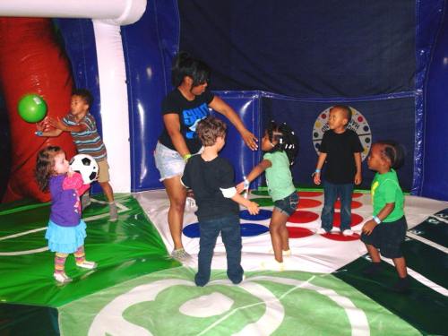 A group of children playing in a colorful inflatable bounce house with a caregiver, engaging in various activities.