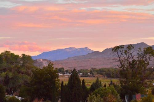 A scenic view of mountains at sunset, with colorful skies and trees in the foreground.