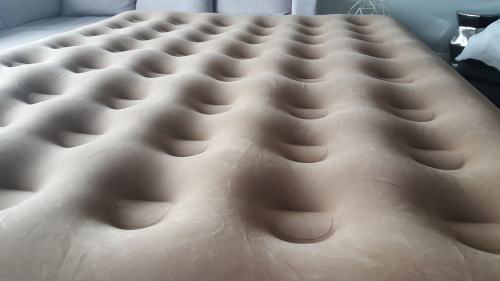 Close-up of a beige air mattress with a textured surface featuring multiple raised bumps.
