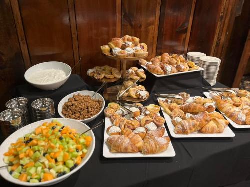 A buffet table featuring croissants, pastries, yogurt, granola, and a fruit salad with melons and berries.