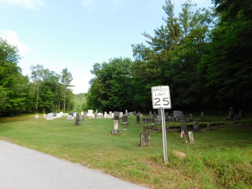 A peaceful cemetery surrounded by trees, with a speed limit sign reading 25 mph in the foreground.