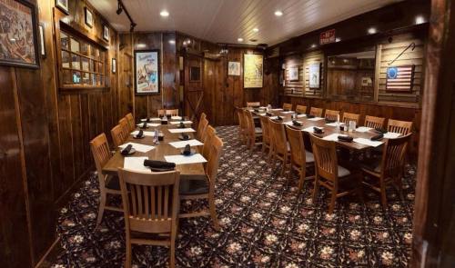 A cozy restaurant interior with wooden walls, a patterned carpet, and tables set for dining.