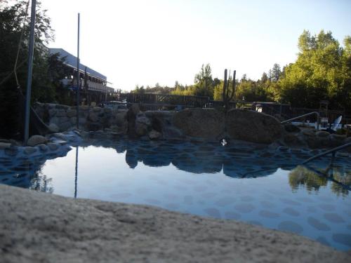 A serene outdoor pool surrounded by rocks and trees, reflecting the sky and nearby buildings in the background.