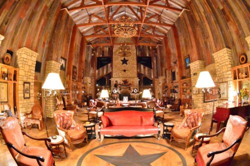 A spacious, rustic library with wooden beams, stone walls, and elegant furniture, featuring a star motif on the floor.