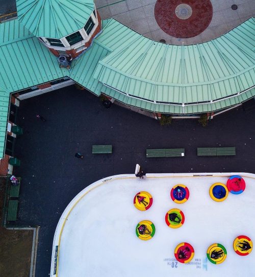 Aerial view of a winter ice rink with colorful inflatable tubes and people enjoying the activity.