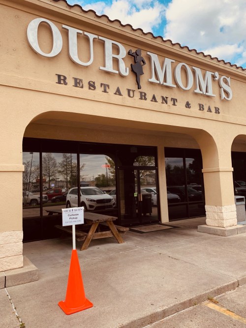 Exterior of "Our Mom's Restaurant & Bar," featuring a sign and a traffic cone in front of the entrance.