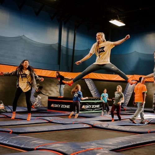 A group of children and teens jumping on trampolines in a vibrant indoor trampoline park.