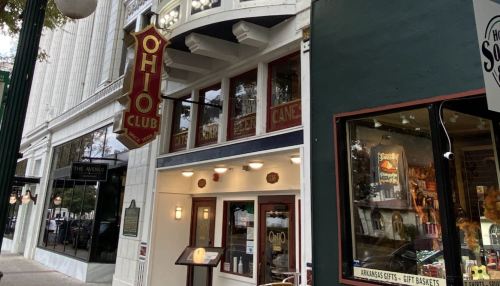 Exterior view of the Ohio Club, featuring a vintage sign and nearby shops in a historic downtown area.
