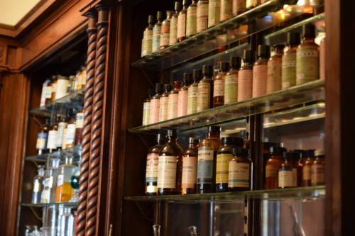 A wooden cabinet filled with various glass bottles and jars, each labeled with different names and contents.