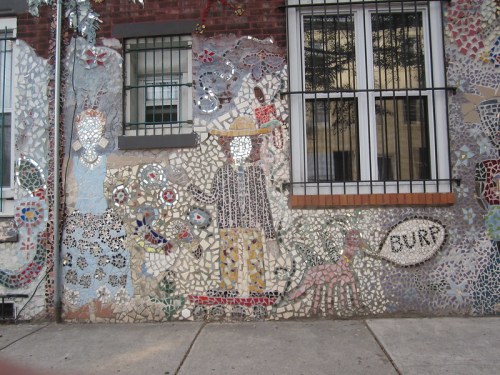 Colorful mosaic mural featuring abstract figures, flowers, and a dog, with the word "BURR" displayed prominently.