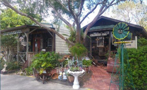 Charming rustic shop surrounded by greenery, featuring vintage decor and garden items in a quaint outdoor setting.