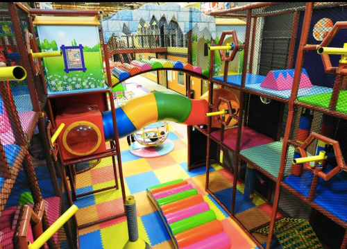 Colorful indoor playground with slides, tunnels, and climbing structures, featuring vibrant flooring and playful designs.
