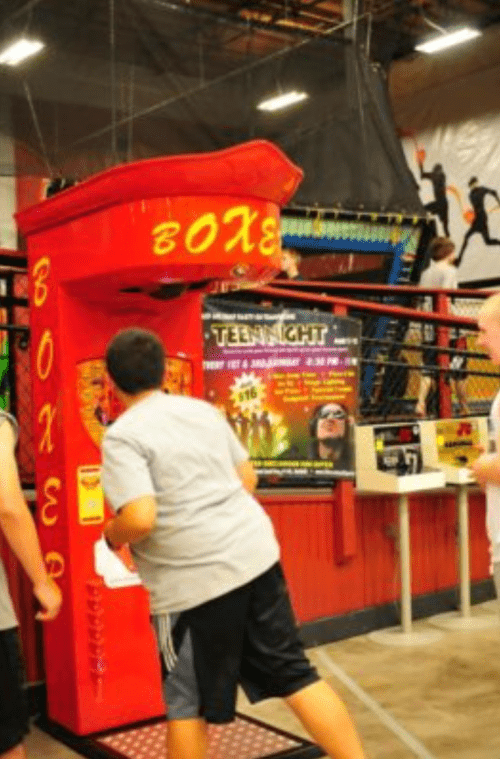 A child plays a boxing arcade game in a vibrant indoor entertainment center.