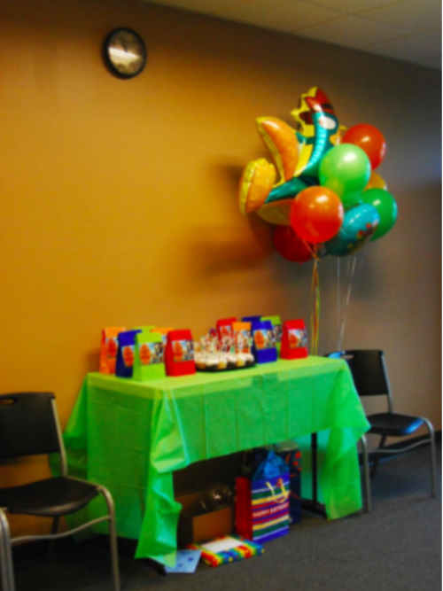 A festive table with a green tablecloth, balloons, and party decorations, set up for a celebration.