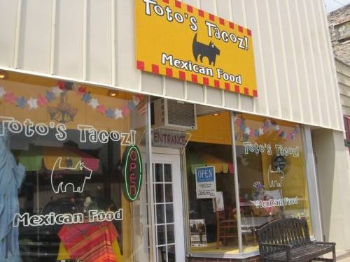 Exterior of Toto's TacoZ, a Mexican food restaurant, featuring colorful signage and an open sign in the window.