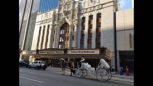 A horse-drawn carriage in front of a historic theater building with ornate architecture and a marquee.