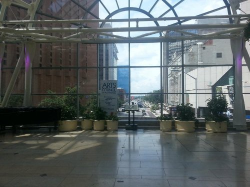 A spacious indoor area with large windows, plants, and a view of a city street outside.