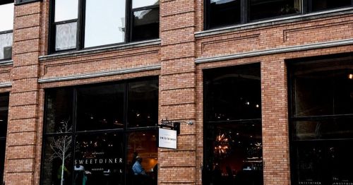 Exterior of a brick building featuring a restaurant sign that reads "Sweet Diner." Large windows showcase the interior.