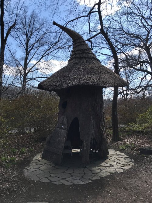 A whimsical, tree-like structure with a thatched roof, surrounded by bare trees and a stone path.