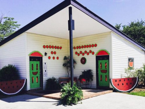 A whimsical building decorated with watermelon-themed designs, featuring bright green doors and red accents.