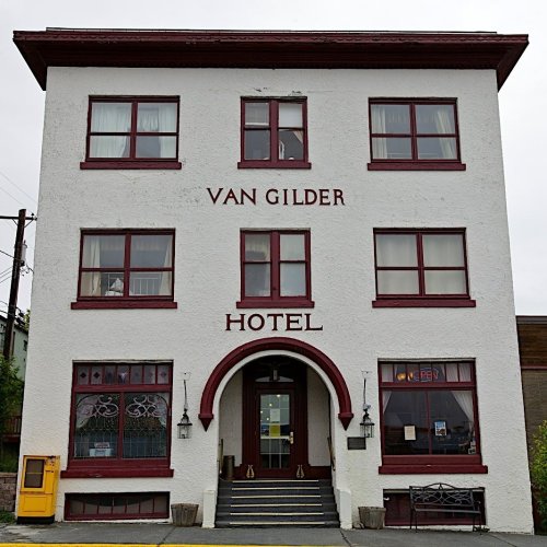 Historic Van Gilder Hotel with a white exterior and red trim, featuring large windows and an arched entrance.