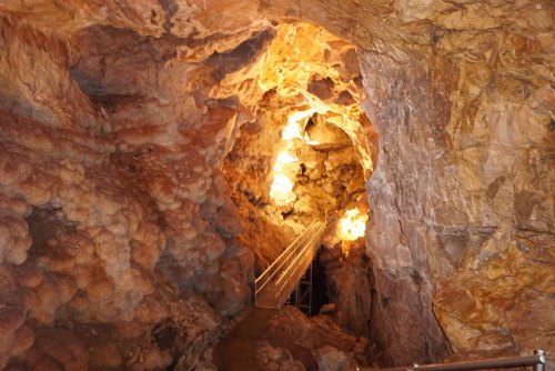 A dimly lit cave interior with rocky walls and a pathway leading deeper into the cavern.
