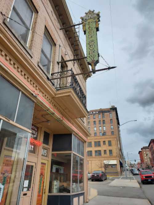 Historic building with a vintage sign, street view featuring cloudy skies and nearby buildings.