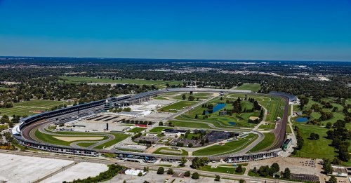 Aerial view of a large racetrack surrounded by green fields and a clear blue sky.