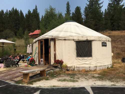 A white yurt labeled "Office" surrounded by greenery, with outdoor seating and a patio area.