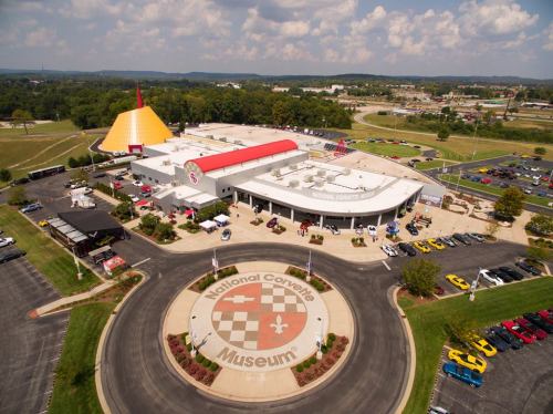 Aerial view of the National Corvette Museum, featuring a distinctive yellow structure and a circular logo in the foreground.